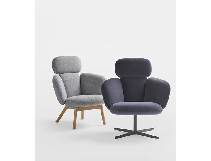 Deux fauteuils contemporains à dossier haut, caractérisés par un assemblage de coussins rembourrés distincts pour l'assise, le dossier et les accoudoirs. À gauche, un modèle en tissu gris clair chiné reposant sur un piétement composé de quatre pieds obliques en bois clair. À droite et au premier plan, un modèle revêtu d'un tissu gris anthracite, monté sur un piétement métallique noir en forme de croix.